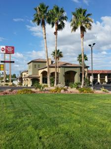 a hotel with palm trees in front of a building at Best Western Plus A Wayfarer's Inn & Suites in Kingman