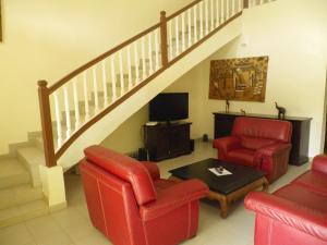 a living room with red chairs and a staircase at Villa la Linguère in Somone