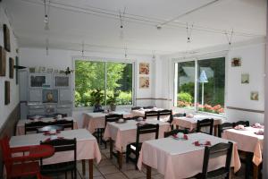 a dining room with white tables and chairs and windows at Hôtel Le Glacier in Gourette