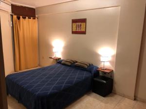1 dormitorio con 1 cama azul y 2 lámparas en Catalina Norte en San Miguel de Tucumán