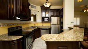 a kitchen with wooden cabinets and granite counter tops at La Ensenada Beach Resort in Tela