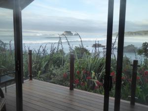 eine Veranda mit Blick auf das Meer und die Blumen in der Unterkunft The Bay House Beachfront Accommodation in Cape Foulwind