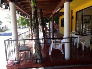 a porch with white tables and chairs on a yellow building at Posada Los Balnearios in San Pedro