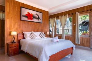 a bedroom with a large white bed with wood paneling at Ware Ware Surf Bungalow Lembongan in Nusa Lembongan