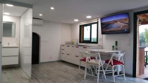 cocina con mesa y TV en la pared en Casita en plena naturaleza con piscina y wifi gratis, en Canet de Mar
