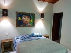 a bedroom with a bed with a painting on the wall at Chalé da Mantiqueira in Socorro