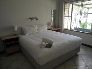 Un dormitorio con una cama blanca con un libro. en Margaret House, en Margaret River Town