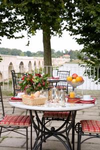 una mesa blanca con cestas de fruta. en Grand Hôtel de l'Abbaye, en Beaugency