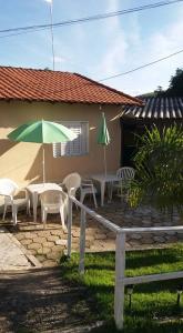 een patio met tafels en stoelen en een parasol bij CHACARA NOSSA SENHORA DAS DORES in Cachoeira Paulista