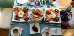 een tafel met borden ontbijtproducten en een kopje koffie bij Freycinet Waters in Swansea