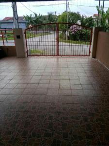 um portão vermelho com piso em azulejo e uma cerca em Homestay Mama Razzin em Kuala Kangsar