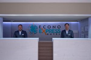 two men in suits are standing behind two desks at Econo Express Hotel in Mexico City