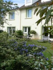 una casa blanca con flores azules delante en Chambres d'Hotes la Raspeliere, en Cabourg