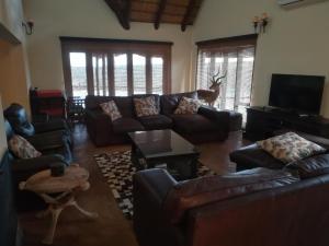 uma sala de estar com sofás de couro e uma televisão em Sunset Private Game Lodge Mabalingwe em Warmbaths