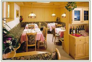 ein Esszimmer mit Tischen, Stühlen und Flaschen Wein in der Unterkunft Hotel Sureghes in St. Ulrich in Gröden