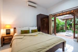 Un dormitorio con una cama grande y una puerta corrediza de vidrio. en Surya Mas Villa, en Legian 26 fotos más