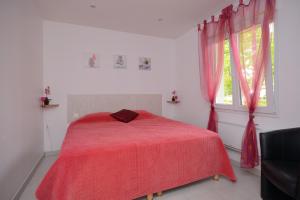 a bedroom with a red bed and a window at Gîtes de charme dans l'Essonne in Buno-Bonnevaux +4 photos