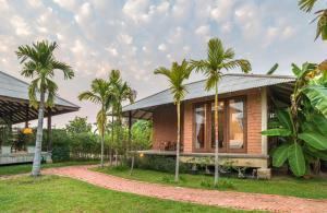 a house with palm trees in front of it at BaanSuk Sukhothai Resort in Sukhothai