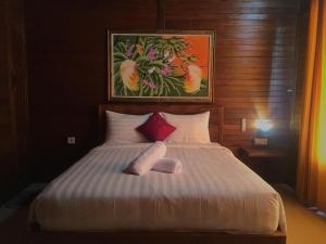 a bed with two pillows and a painting on the wall at Bamboo Bungalow Jungle View in Nusa Penida