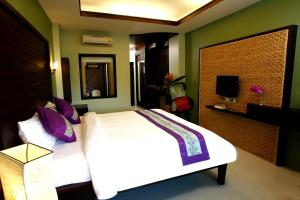 1 dormitorio con 1 cama blanca grande con almohadas moradas en Lamoon Lamai Residence & Guesthouse, en Lamai