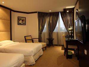 um quarto de hotel com duas camas e uma secretária e uma televisão em Country Hotel em Klang