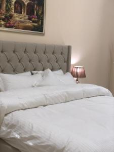 a large white bed with a large headboard and a lamp at Al Rawda Apartments -Ajman in Ajman 