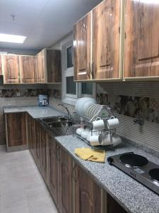 a kitchen with wooden cabinets and a counter top at Al Rawda Apartments -Ajman in Ajman  +52 photos