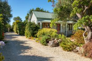 a house with a gravel driveway in front of it at Shy Cottage and Studio in Greytown