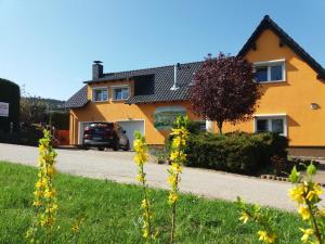 a yellow house with a car parked in the driveway at Ferienwohnung Isabella in Crostau