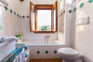 Un baño con bañera, inodoro y ventana. en Brassol Casa Vacanze Vista Mare, en Alghero