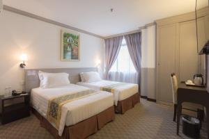 a hotel room with two beds and a desk at Hallmark Leisure Hotel in Melaka
