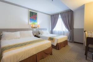 una camera d'albergo con due letti e una finestra di Hallmark Leisure Hotel a Malacca