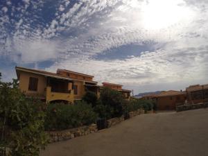 a cloudy sky above a house with flowers and bushes at Residence Spiaggia Bianca in Golfo Aranci