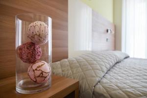 two flowers in a glass vase on a table next to a bed at Hotel St Pierre in Rimini