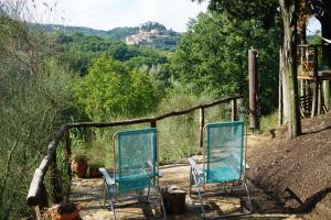 2 sillas sentadas en un porche con vistas a las montañas en Agriturismo Il Caio, en Cetona