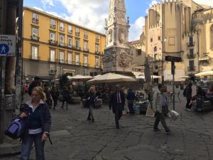 een groep mensen die rond een straat lopen met een klokkentoren bij La Piccola Reggia in Napels