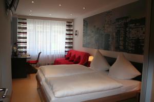 ein Schlafzimmer mit einem weißen Bett und einem roten Stuhl in der Unterkunft Gasthof Wimmer Weissbräu in Simbach am Inn