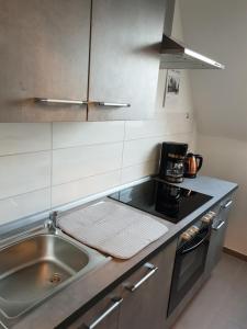 uma pequena cozinha com um lavatório e um fogão em Ferienwohnung Helena em Emden