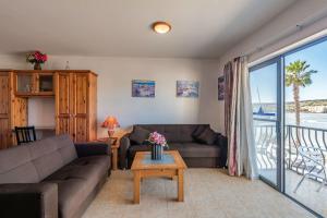 uma sala de estar com um sofá e uma mesa em Harbour Lights seafront 2 bedroom apartments with panoramic sea views - by Getawaysmalta em St. Paul's Bay