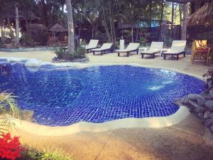 a large blue pool with chairs in a yard at Papillon Bungalows in Ko Lanta