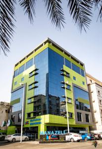 een geel en blauw gebouw met auto's ervoor geparkeerd bij Manazeli Jeddah - in Jeddah