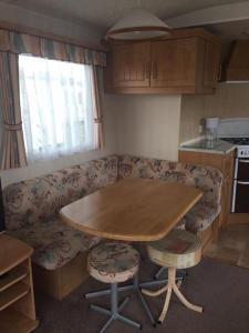 uma pequena cozinha com uma mesa e um sofá em 8 BERTH CARAVAN TP49 ON THE GOLDEN PALM CHAPEL ST LEONARDS em Skegness
