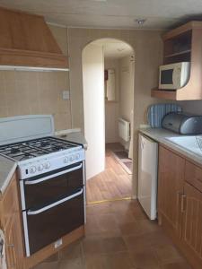 a kitchen with a stove and a counter top at 8 BERTH CARAVAN TP49 ON THE GOLDEN PALM CHAPEL ST LEONARDS in Skegness