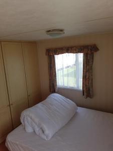 uma cama num quarto com uma janela em 8 BERTH CARAVAN TP49 ON THE GOLDEN PALM CHAPEL ST LEONARDS em Skegness