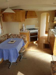 a kitchen with a table with a blue table cloth on it at 8 BERTH CARAVAN TP49 ON THE GOLDEN PALM CHAPEL ST LEONARDS in Skegness