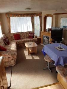 uma sala de estar com um sofá e uma mesa em 8 BERTH CARAVAN TP49 ON THE GOLDEN PALM CHAPEL ST LEONARDS em Skegness