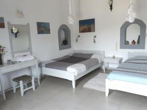 a bedroom with two beds and two tables and mirrors at Aloni in Kamilari
