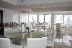 comedor con mesa de cristal y sillas blancas en Les Palmiers Beach Boutique Hotel & Luxury Apartments, en Lárnaca