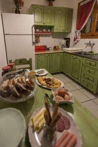 a kitchen with green cabinets and plates of food on a table at Το Ηλιοβασίλεμα in Méga Khoríon
