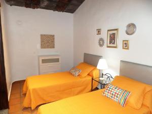 2 Betten in einem Zimmer mit orangefarbener Bettwäsche in der Unterkunft Apartamento rural Los Roferos in Guatiza